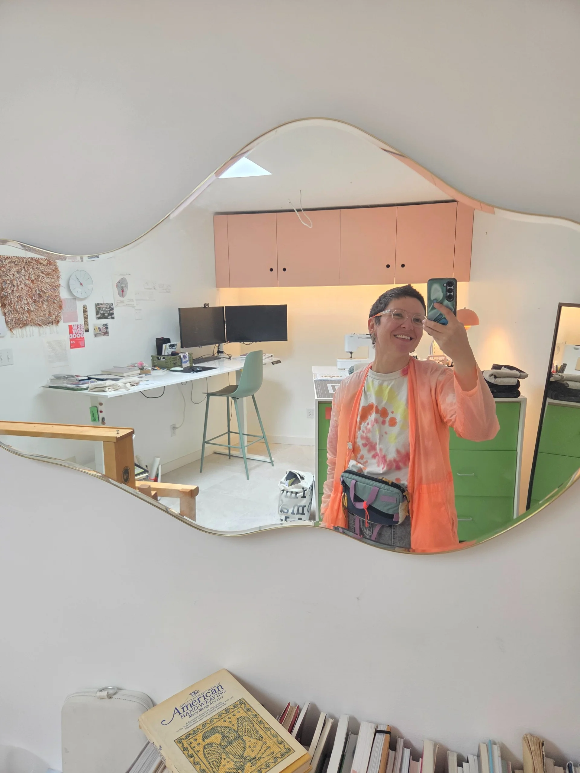 Varvara in her studio with her sewing machine, reflected in a wavy-edged mirror