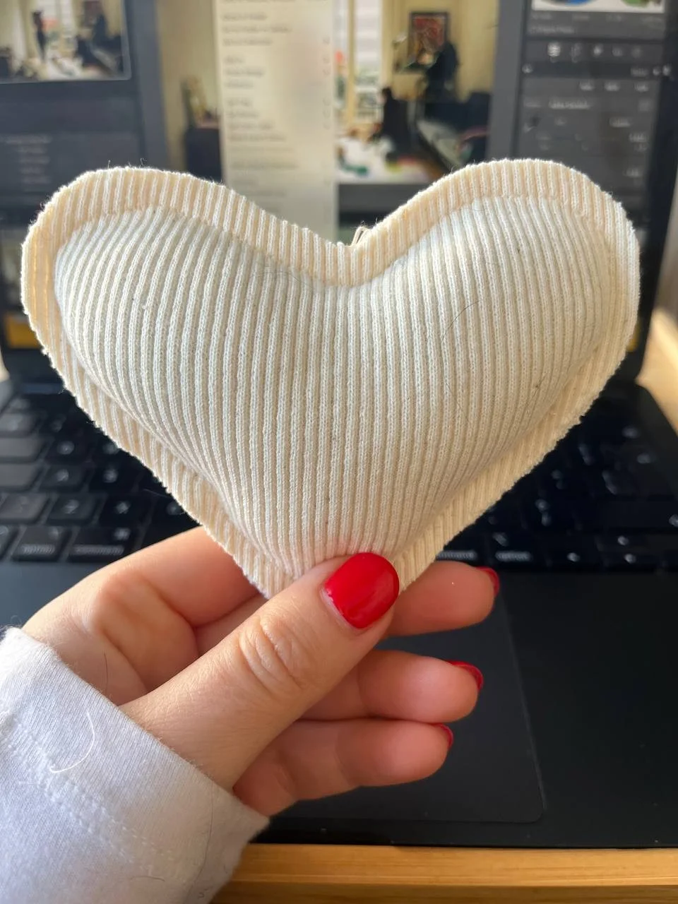 A soft cream knitted heart held in hand — 100% love, 0% waste