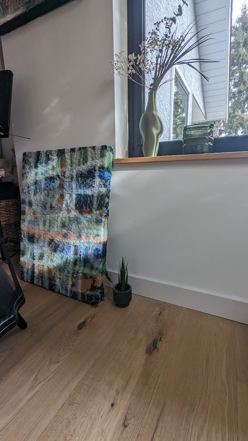 The work at an earlier stage, leaning by a window with dried flowers on the sill