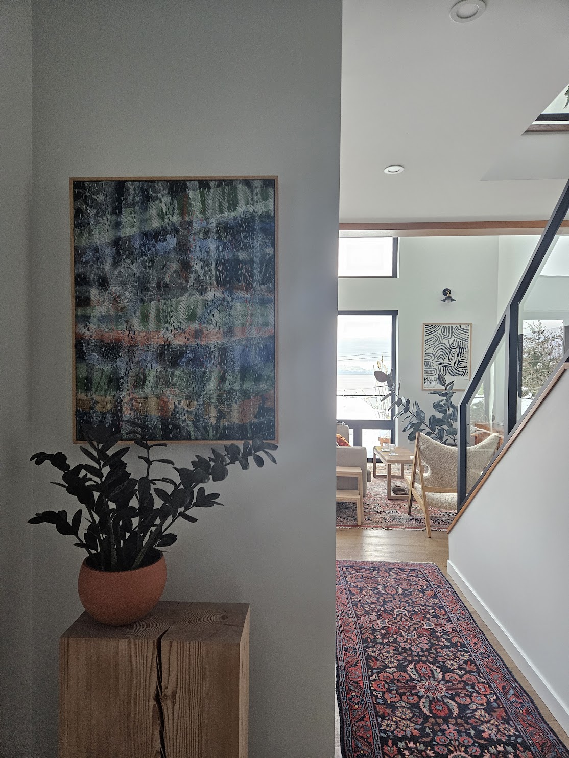 The framed work hung in a bright hallway, with an ocean view through the windows beyond